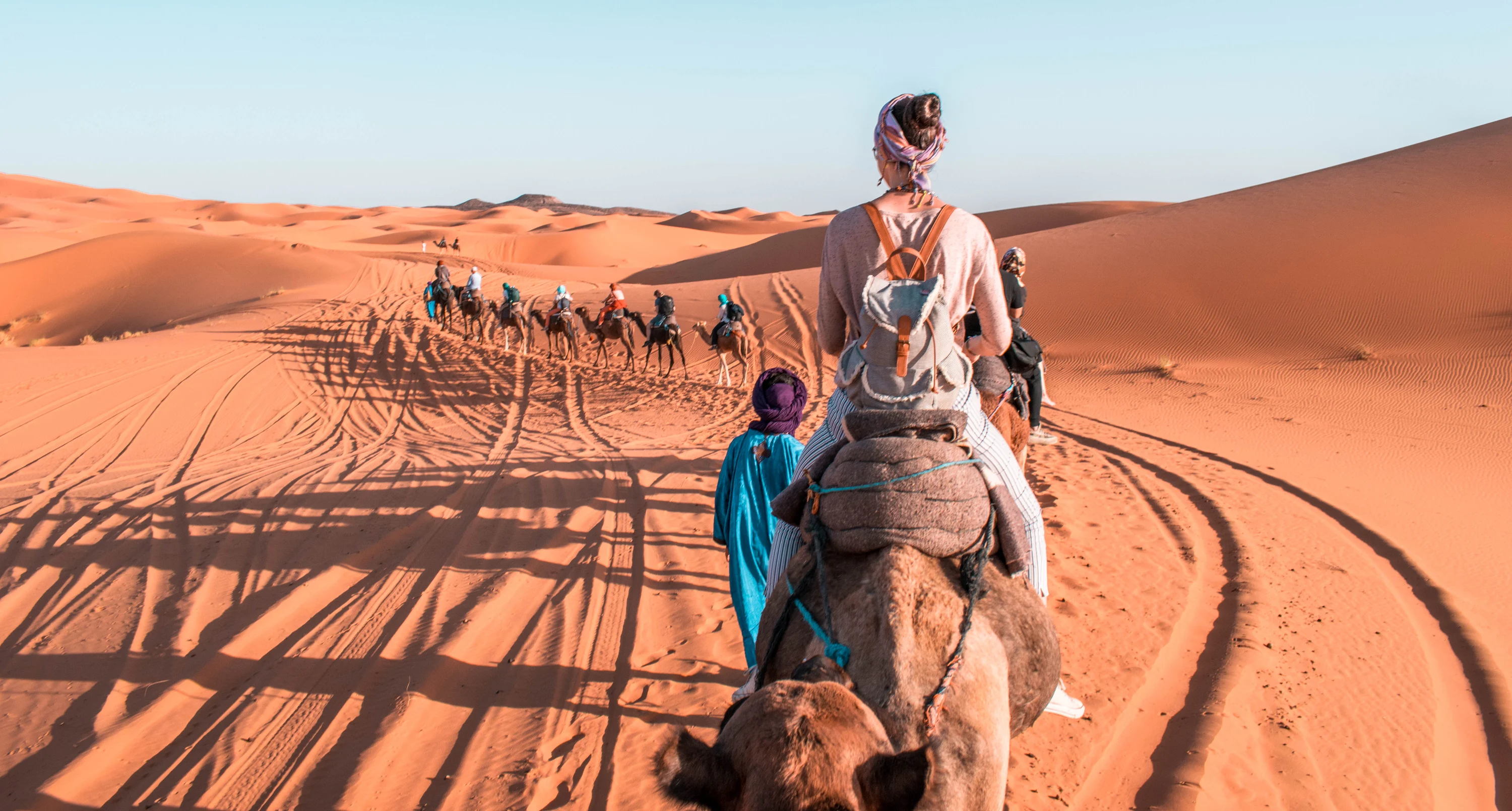 Camel trekking at sunset over the Erg Chebbi sand dunes in Merzouga, Morocco